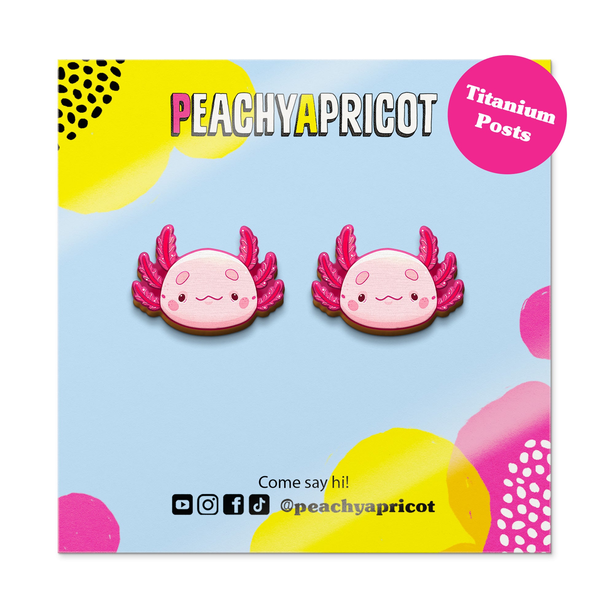 Pair of pink axolotl-shaped earrings on a colorful packaging with 'Peachy Apricot' branding.