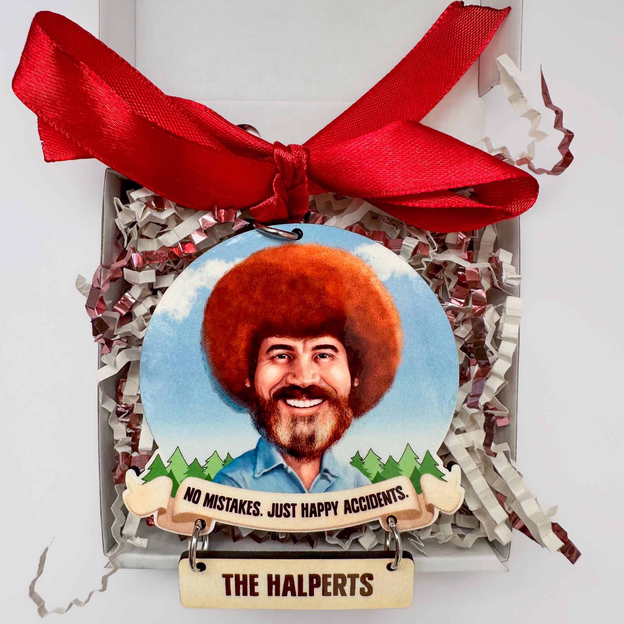Decorative ornament with a portrait of Bob Ross with a red bow and gift box