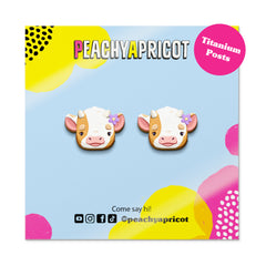 Cow-shaped earrings on a colorful card with 'Peachy Apricot' branding.