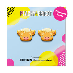 Peachy Apricot cow-shaped earrings on a colorful branded card.
