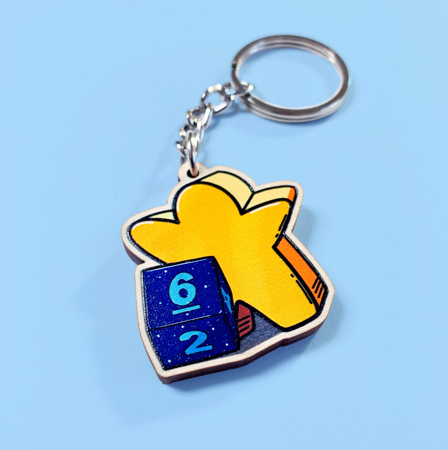 Keychain with a blue die and yellow meeple on a light blue background