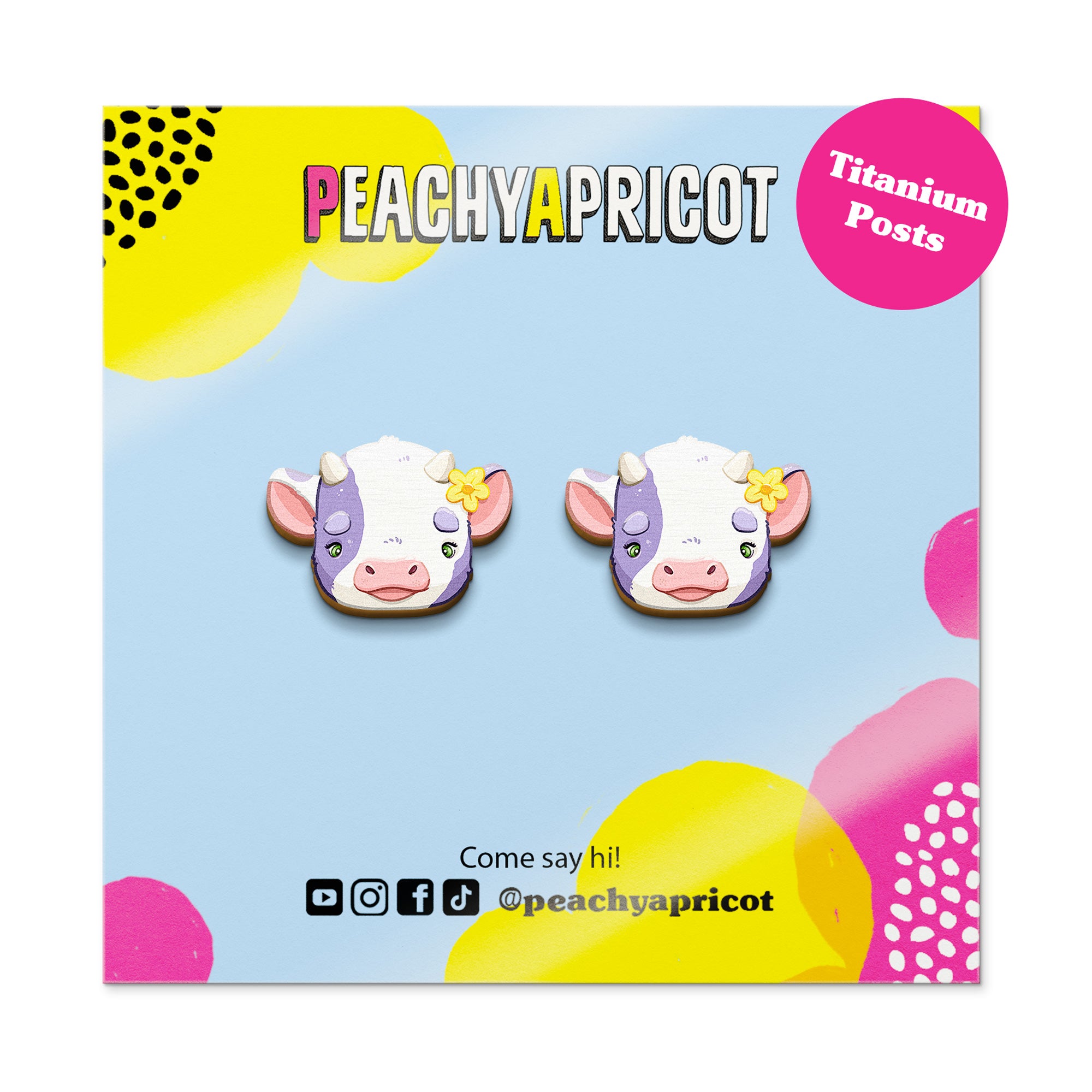 Cartoon cow earrings on a colorful card with 'Peachy Apricot' branding.