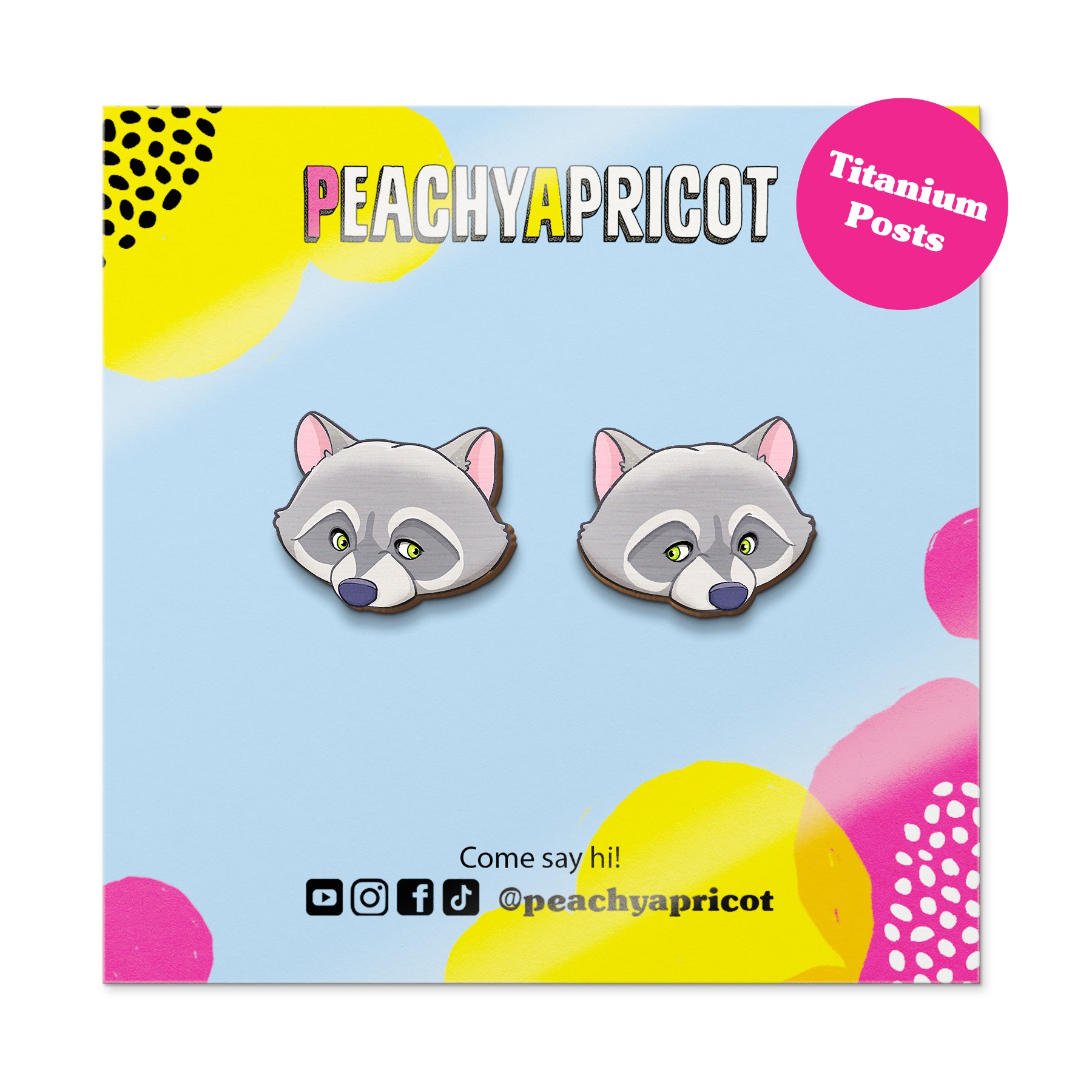 Raccoon-shaped earrings on a colorful packaging with 'Peachy Apricot' branding.