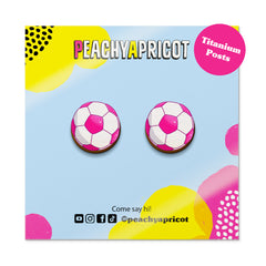 Pair of pink and white soccer ball earrings on a colorful 'Peachy Apricot' branded card.